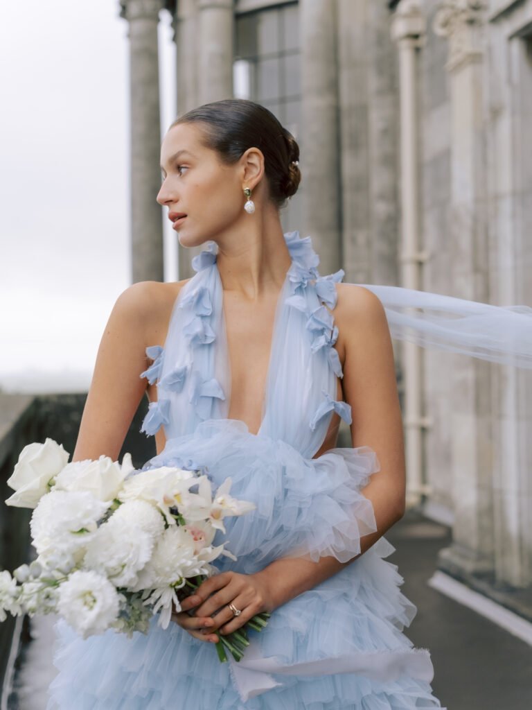 Bride in powder blue dress holding bouquet of neutral coloured flowers created by Winter and the Willows