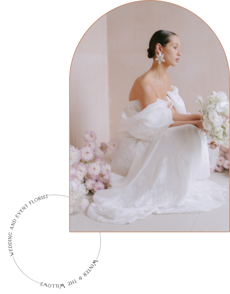 Bride holding a beautiful bouquet of flowers, surrounded by floral designs from Winter and the Willows